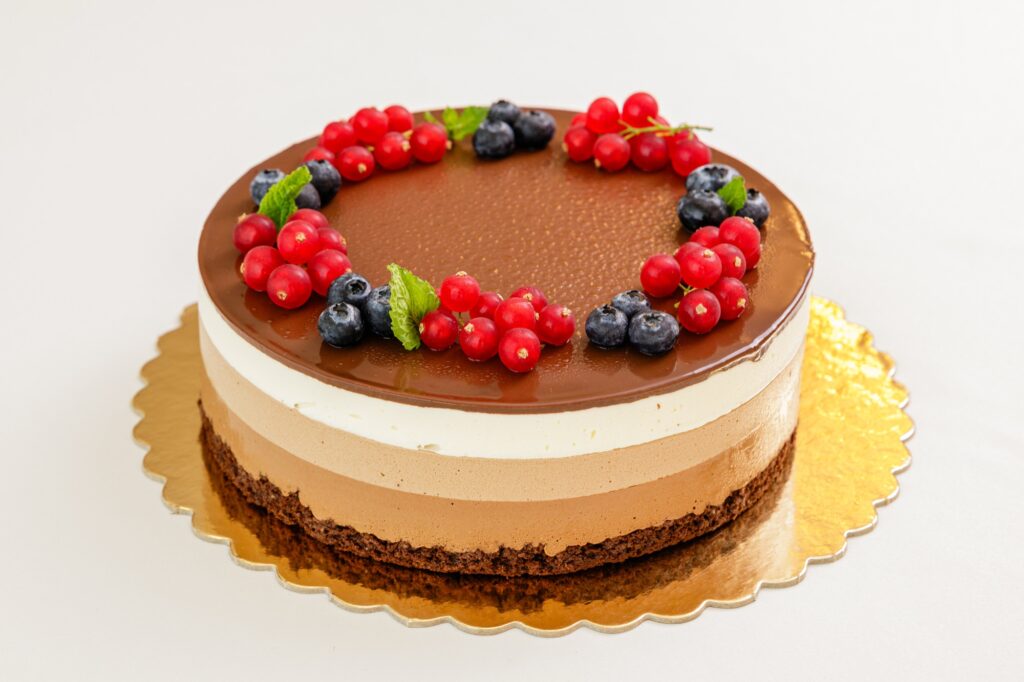Tort mousse de ciocolată în straturi, decorat cu fructe de pădure.