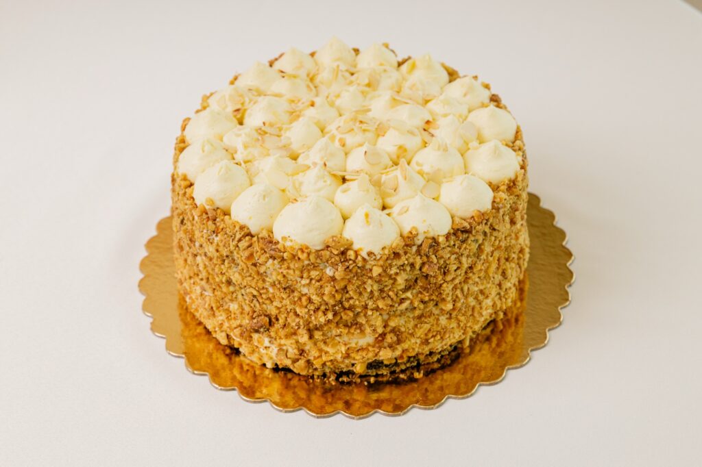 Tort cu blat crocant de nuci și frișcă, decorat cu rozete de cremă.