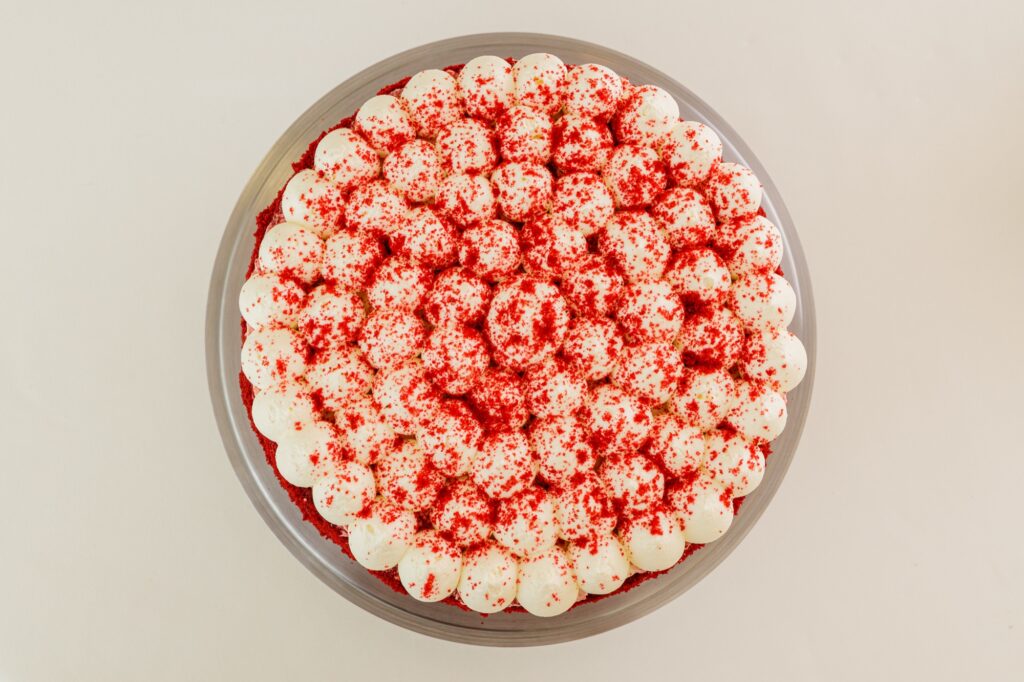 Tort red velvet cu rozete de cremă și pesmet roșu, vedere de sus.