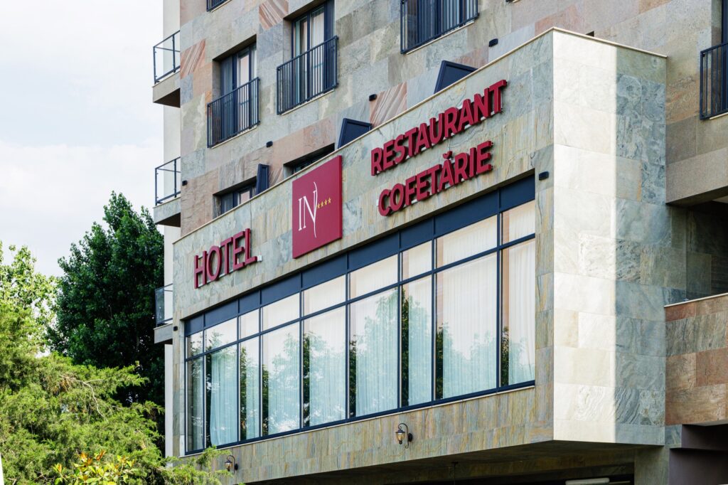 Intrarea hotelului cu firma „Hotel · Restaurant · Cofetărie”.