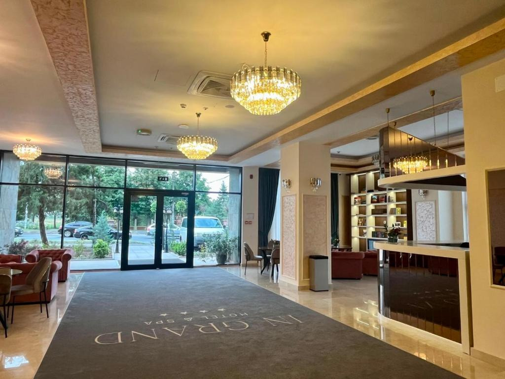 Receptia hotelului In Grand Hotel&SPA, amenajata elegant cu candelabre, canapele si biblioteca
